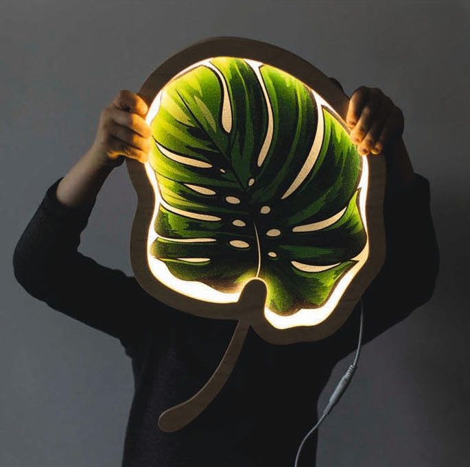 Drewniana lampka LED w kształcie liścia Monstera, świecąca ciepłym światłem, idealna do dekoracji wnętrza w stylu naturalnym.