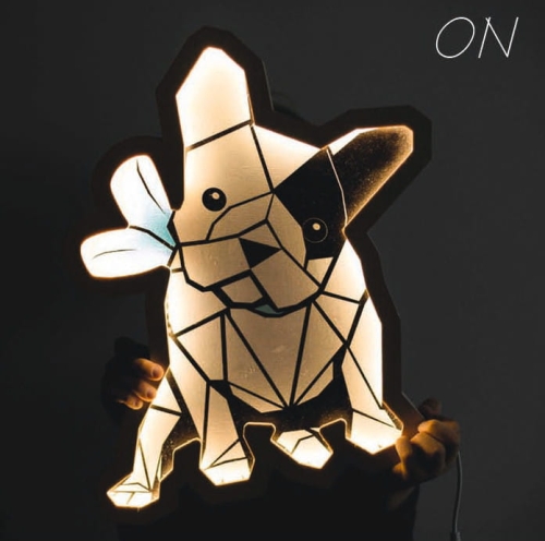 Lampka nocna LED w kształcie buldoga francuskiego, wykonana ze sklejki brzozowej, świecąca ciepłym światłem, zamontowana na ścianie lub postawiona na komodzie w pokoju dziecięcym, idealna dla małych miłośników zwierząt.