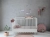 Białe łóżeczko Babushka 70x140 cm w stylu retro, z regulacją wysokości materaca i możliwością przekształcenia na łóżko dla starszego dziecka.