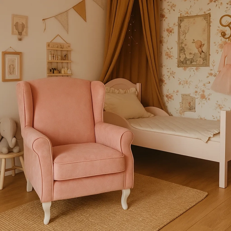Fotel uszak w kolorze pudrowego różu z aksamitnej tkaniny velvet w stylu vintage, ustawiony w pokoju dziewczynki obok łóżeczka z baldachimem i tapetą w kwiaty