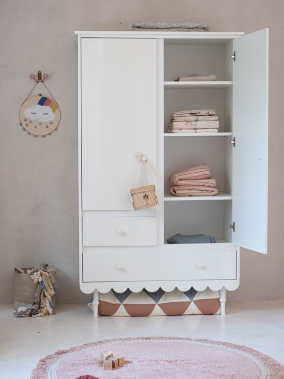 Szafa dwudrzwiowa Babushka w stylu retro, biała z ozdobnymi nóżkami i falbanką u dołu, idealna do pokoju dziecięcego. Posiada szuflady, półki i miejsce na wieszaki. Stylowy mebel polskiej marki Wood Luck Design.